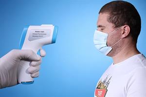 800px-Hand_with_surgical_gloves_aiming_infrared_thermometer_at_a_man_with_mask_on_blue_background.jpg